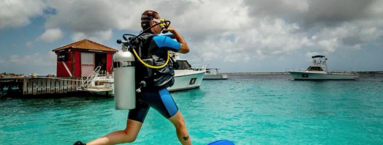 A scuba diver does a giant stride to enter the water at Captain Don's Habitat dive resort in Bonaire