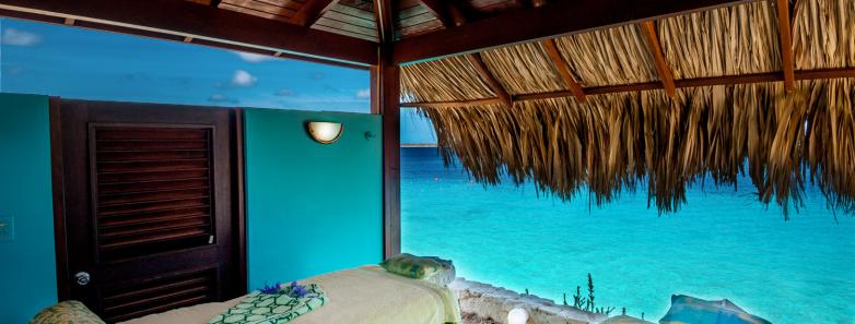 Two massage tables under a thatch roof next to the sea at Captain Don's Habitat dive resort in Bonaire