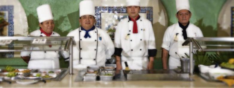 A group of chefs at Cozumel Palace hotel in Mexico, standing behind a counter, preparing delicious dishes.