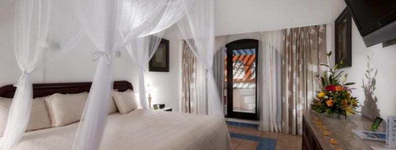 A cozy bedroom at Cozumel Palace hotel in Mexico, featuring a comfortable bed and a television.