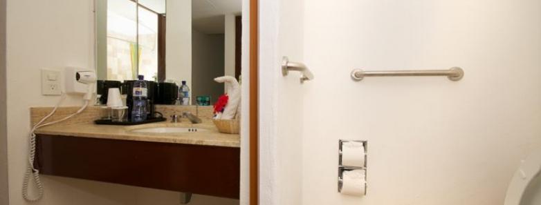 A bathroom in Cozumel Palace hotel, Mexico, featuring a toilet, sink, and mirror.
