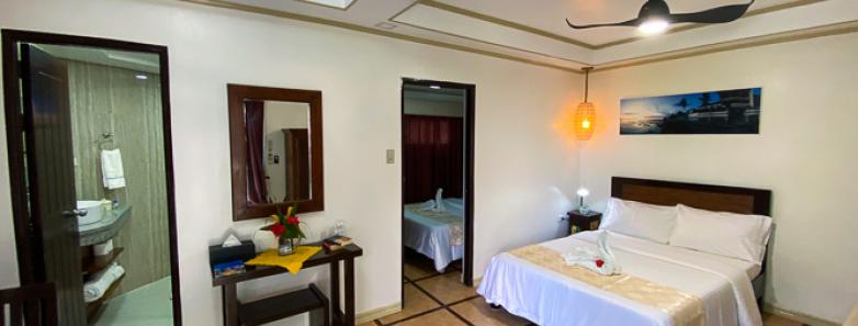 Spacious bedroom with a comfortable bed and a TV at Crystal Blue Resort in Anilao, Philippines.