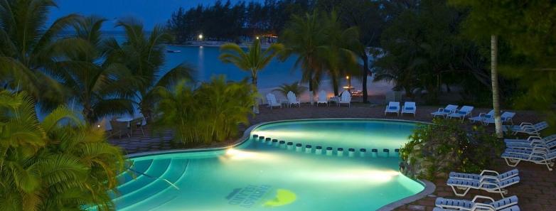 A swimming pool lit up at night at Fantasy Island Roatan Resort.