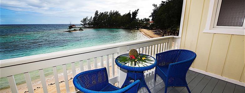 Chairs on a balcony overlook the beach and ocean at Fantasy Island Roatan Resort.