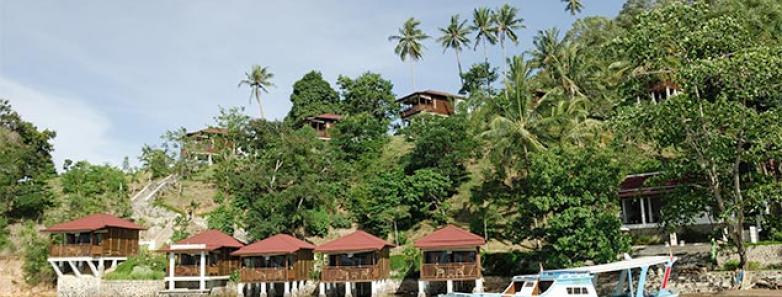 Wooden bungalows sit along the water's edge and hillside.