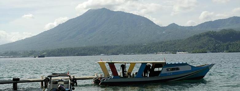 Dive boats at a dock with mountains in the background.