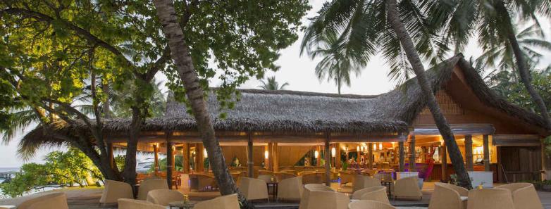 An outdoor restaurant with tables in the white sand at Kuramathi Island Resort Maldives.
