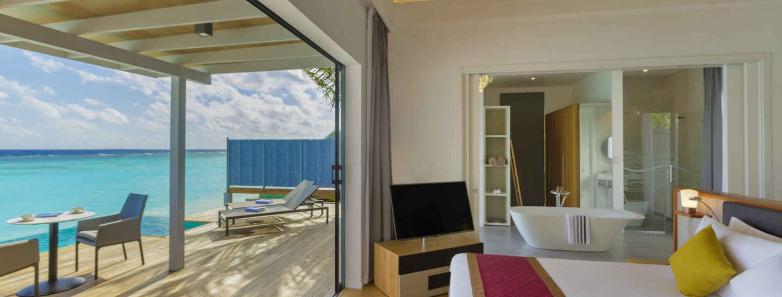 A bed look out onto the sea in a pool villa at Kuramathi Island Resort Maldives.