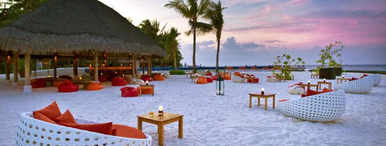 Lounge chairs on a white sand beach at Kuramathi Island Resort Maldives.