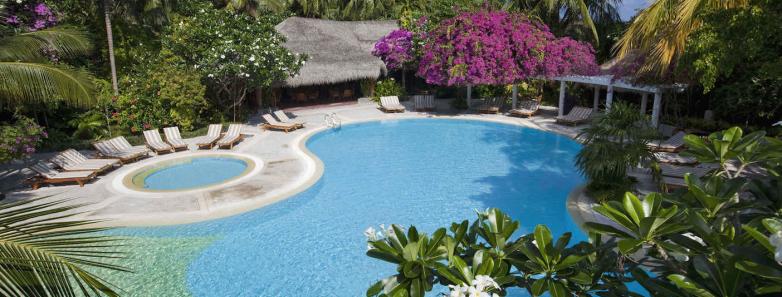 A large swimming pool surrounded by lush foliage at Kuramathi Island Resort Maldives