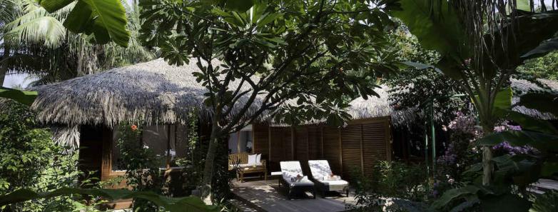 A beach bungalow nestled into the trees at Kuramathi Island Resort Maldives.