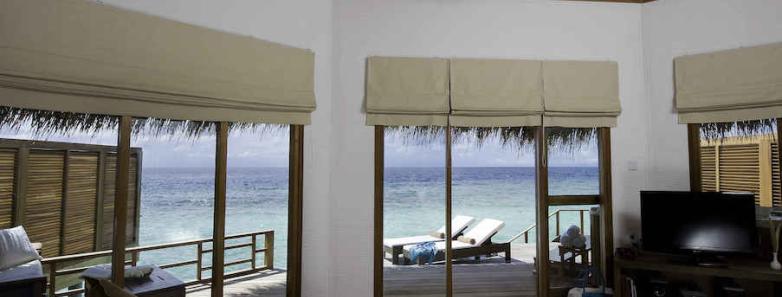 A water villa bedroom with a sea view at Kuramathi Island Resort Maldives.