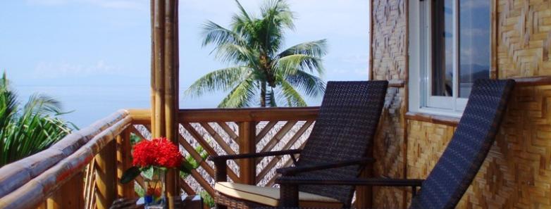 A cottage deck with chairs and a table at Magic Island Dive Resort.
