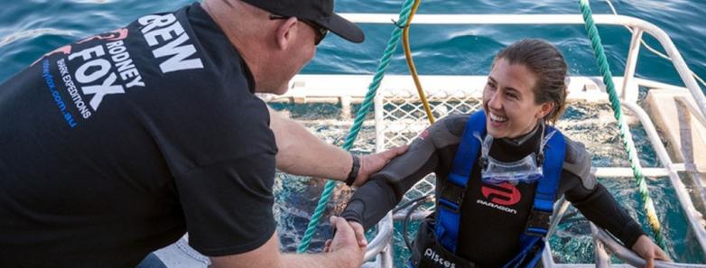 A diver is helped out of a cage with Rodney Fox Shark Expeditions