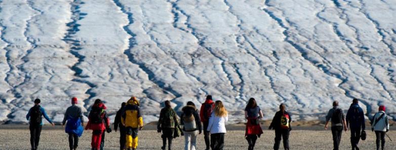 A group of people approach a glacier on foot