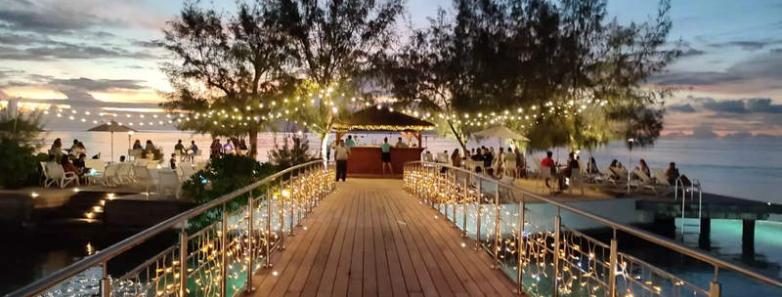 An over-water walkway adorned with strings of lights at Te Moana Tahiti Resort