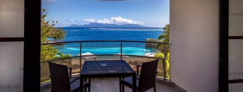 A table and two chairs on a balcony with a sea view at Te Moana Tahiti Resort