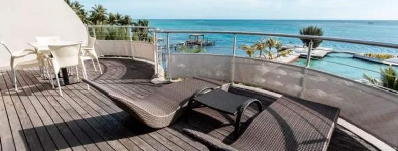 Sun loungers and dining table on a balcony with a sea view at Te Moana Tahiti Resort