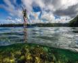 A person paddleboards over a reef at Tufi Resort Papua New Guinea